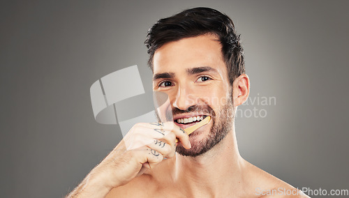 Image of Man, brushing teeth and dental healthcare for beauty smile or grooming morning routine with toothbrush in studio. Face, smile and hygiene health with model cleaning teeth portrait in grey background