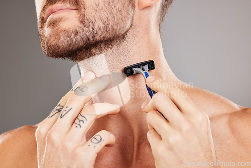 Image of Grooming, beard and man shaving hair for skincare, wellness and health against a grey studio background. Dermatology, hygiene and hands of a model with a razor to shave neck for a fresh treatment