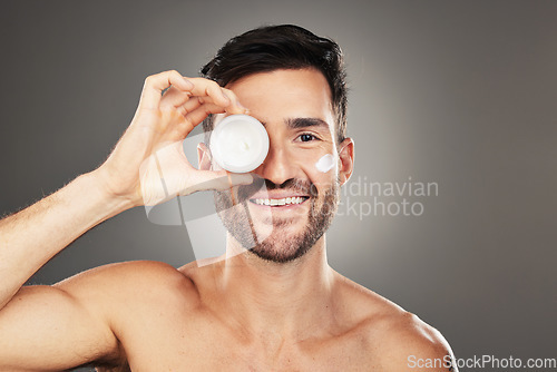 Image of Face, skincare and product with a man model in studio on a gray background to promote beauty treatment. Portrait, container and antiaging with a handsome young male posing for wellness or care