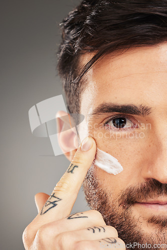 Image of Man, face and cream for beauty, skincare and wellness with hand against a grey studio background with mockup. Male model with facial lotion on sunscreen lotion for skin health and protection from uv