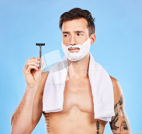 Image of Shave, razor and man with shaving cream and towel for grooming, beauty and skincare against blue studio background. Clean, hygiene and face product in hand with fresh skin and hair removal mockup.