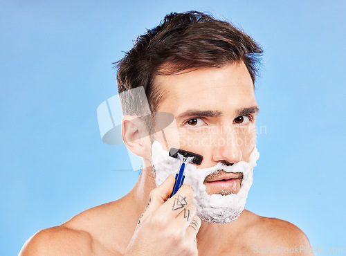 Image of Facial, shave and razor portrait of man for hygiene, cleaning and self care routine for healthy skin. Wellness, health and face of model with beard foam on blue studio mock up for advertising.