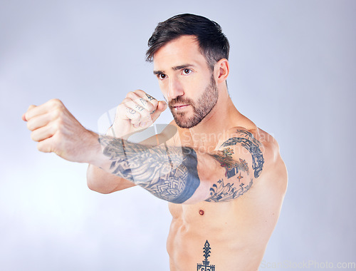 Image of Man, boxing and punching on studio background in fitness workout, body training or exercise for competition fight, anger management or stress control. Boxer, sports athlete and mma model with tattoos