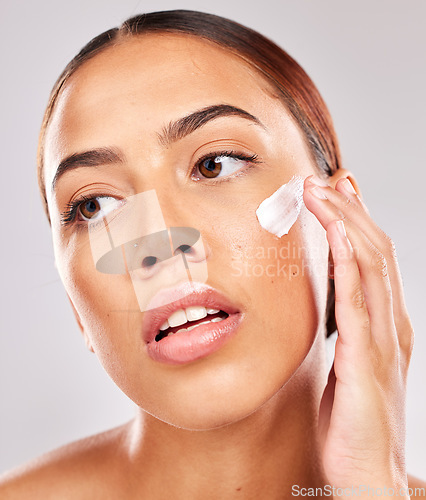 Image of Face, beauty and skincare with a model black woman using moisturizer on her skin in studio on a gray background. Wellness, cosmetics and cream with a female posing to promote antiaging treatment