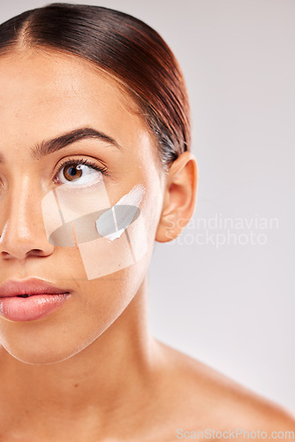 Image of Face, beauty and skincare with a model black woman in studio on a gray background for skin hydration. Costmetics, antiaging and moisturizer with an attractive young female with cream on her cheek