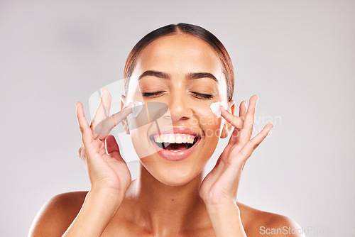 Image of Skincare, beauty and woman with face cream in a studio doing a natural face and skin routine. Cosmetic, wellness and happy girl model with facial lotion, spf or sunscreen isolated by gray background.