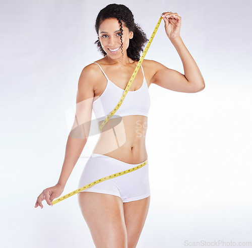 Image of Weight loss, measure tape and wellness of a black woman beauty model with stomach measurement. Portrait of a woman checking health, diet and healthy fitness progress feeling happy with a smile