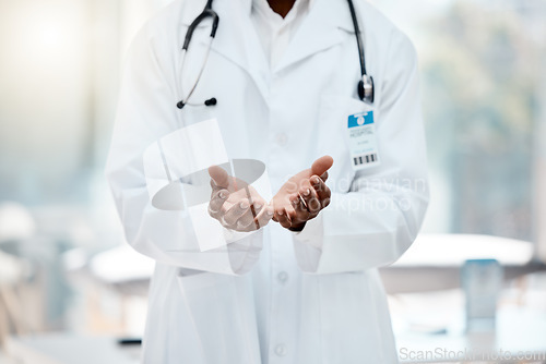 Image of Doctor, hands and open in hospital for help, healthcare or medical support with welcome, care and trust. Black doctor, medic man and health worker in clinic, empty palm and stethoscope in workplace