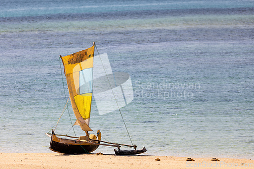 Image of Tranquil scene of a wooden fishing boat resting on the golden sands of Nosy Ve, Madagascar