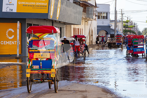 Image of Traditional rickshaw bicycle with Malagasy people on the street of Toliara, one of the ways to earn money. Everyday life on the street of Madagascar.