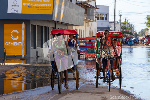 Image of Traditional rickshaw bicycle with Malagasy people on the street of Toliara, one of the ways to earn money. Everyday life on the street of Madagascar.