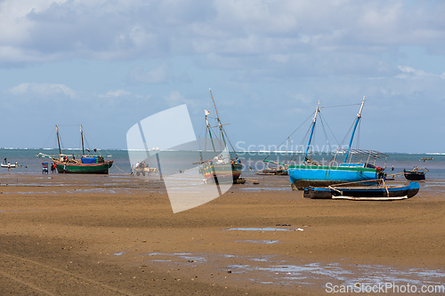 Image of Fishing boat stranded on the dry port during low tide with Malagasy people around.