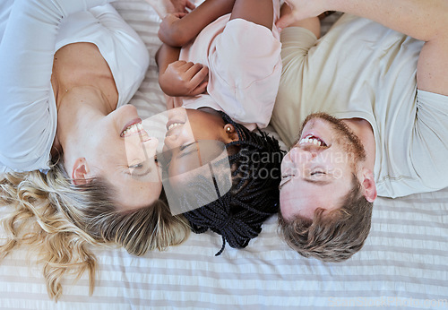 Image of Family, love and happy together with care in family home, smile in overhead with adoption or foster care. Happy family, interracial and happiness with mother, father and child lying on bed bonding.