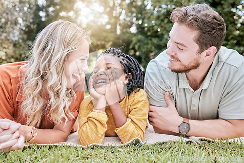 Image of Family, adoption and picnic on blanket in park with mother, father and black girl in nature, relax and happy. Diversity, kid and parents relaxing on grass in the yard, enjoy summer with love or smile