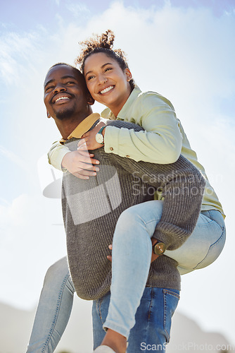 Image of Happy, couple and piggy back enjoy fresh air on vacation outdoor with blue sky background. Smile, black man and happiness woman being playful and having fun together on a romantic date in nature park