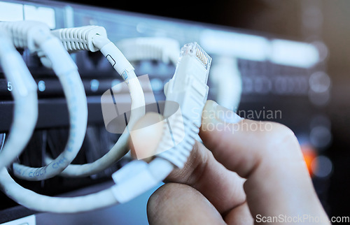 Image of Hand on network cable in server room or data center for maintenance on server machine. Technology, connection and wires in datacenter, information storage and hands of engineer or technician closeup.