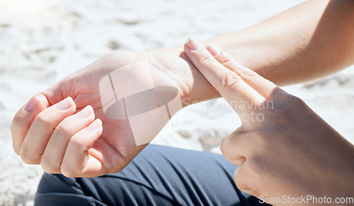 Image of Woman, hand and check pulse, heartbeat and wrist with finger outdoor after workout, training or cardio. Person, hands and monitor heart rate after healthy workout or body activity in nature at beach