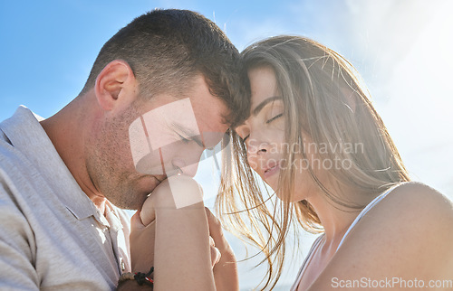 Image of Love, hand and couple kiss at a beach, sharing intimate moment of romance at sunrise against blue sky background. Travel, freedom and man with woman embrace, care and relax in nature together mockup