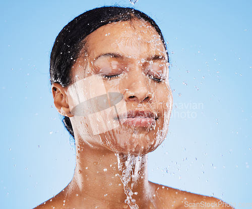 Image of Woman, shower and water splash on face for skincare hydration or clean hygiene against blue studio background. Female in facial wash with water to hydrate or cleanse for hygienic body care treatment