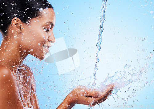 Image of Water, splash and black woman doing skincare for health, wellness and hygiene in a studio. Beauty, shower and girl model doing a natural treatment for skin, body or face with aqua by blue background.