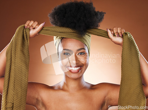 Image of Face, beauty and black woman with hair scarf in studio on brown background. Fashion, haircare and happy female model tying her afro with fabric head wrap for unique hairstyle and healthy conditioner.