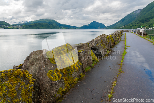 Image of Mossy stones on a breakwater with mountains and sea