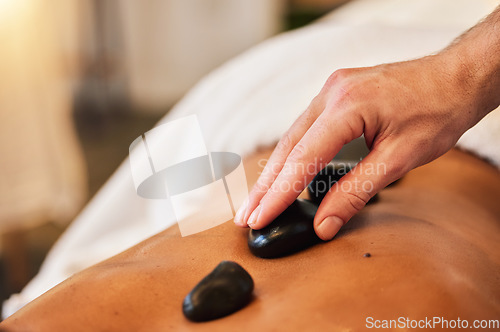 Image of Hot stone massage, spa and skincare for wellness, health and physical therapy to relax in luxury. Mind, body and spirit wellness with rock therapy on skin in closeup with oil, zen or natural cosmetic