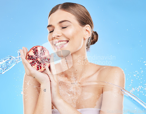 Image of Beauty, water and pomegranate with a model woman in studio on a blue background for nutrition or hydration. Food, cleaning and skincare with an attractive young female posing to promote health