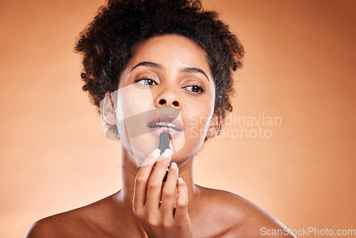 Image of Lipstick, black woman and cosmetics for smooth, glow and skincare with confidence with brown studio background. Lips, African American female and girl with gloss, makeup and natural beauty for mouth