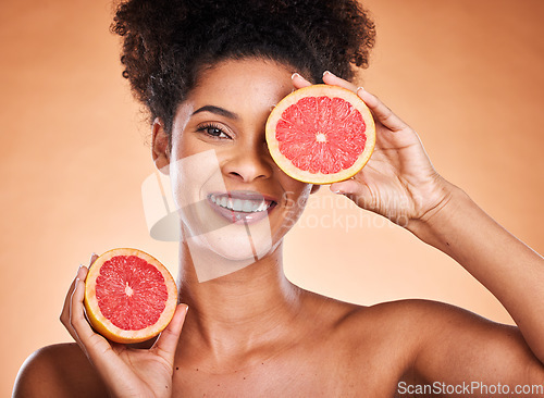 Image of Grapefruit, skincare and portrait of black woman with a beauty, organic and natural routine. Cosmetics, citrus fruit and African model with cosmetic facial treatment in studio with orange background.