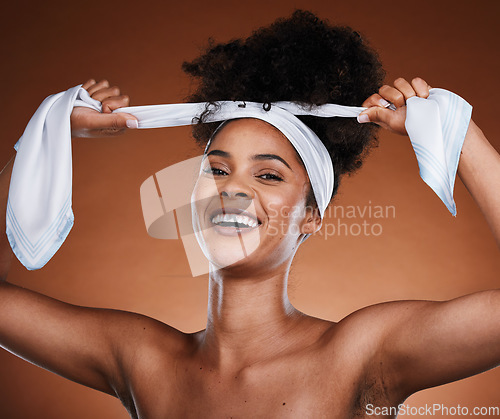 Image of Face, beauty and hair with a model black woman in studio on a brown background for natural haircare. Portrait, hairstyle and tying with an attractive young female posing to promote keratin treatment