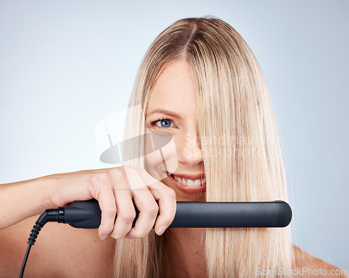 Image of Hair care, flat iron and woman advertising beauty product, cosmetics and smile on grey mockup studio background. Happy female model, healthy hair and wellness with electronic device or technology