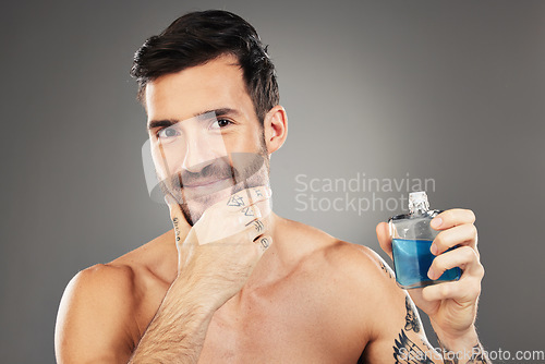 Image of Man, perfume and cologne product in studio for hygiene, fresh scent and fragrance on gray background. Parfum, wellness and happy male model thinking about spray cosmetics to prevent odor or smell.