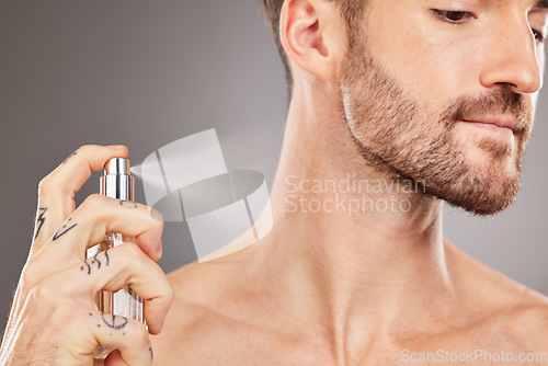 Image of Hand, perfume and beauty with a man model spraying cologne in studio on a gray background for fresh scent. Product, luxury and spray with a handsome young male inside to apply an aroma for smell