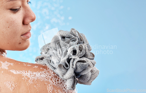 Image of Shower, cleaning and loofah with a woman in studio on a blue background for water hydration or hygiene. Skincare, wellness and beauty with a female washing in the bathroom for luxury body care