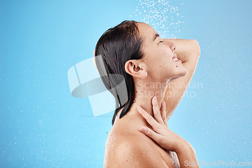 Image of Skincare, woman and shower with water, for wellness and body care against blue studio background. Female, girl and wet for cleaning, washing and splash for hygiene, health and grooming to relax.