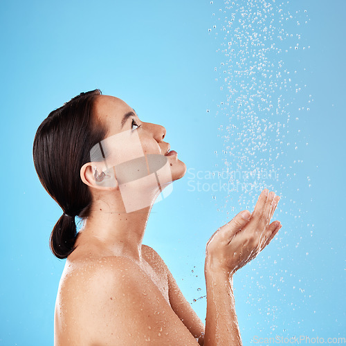 Image of Water, shower and woman washing in a studio for body care, hygiene and to stop germs or bacteria. Health, wellness and Asian model cleaning her skin with aqua while isolated by a blue background.
