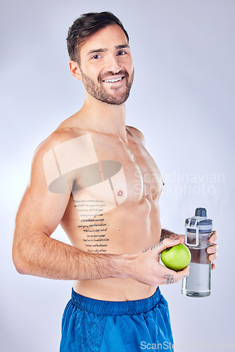 Image of Water bottle, apple and healthy man in studio portrait for diet, clean body and fitness marketing or advertising. Sports, strong and gym model with muscle wellness, healthy food and fruit nutrition