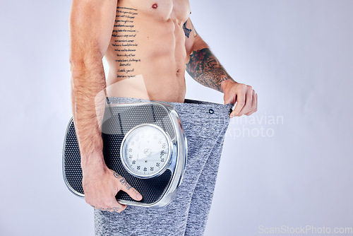 Image of Motivation, health and weight loss, man with scale checking change from diet, workout and healthy lifestyle on studio background. Fitness, nutrition and wellness, balance in body care for male model.