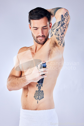 Image of Beauty, fresh and deodorant with a man model spraying perfume to his underarm in studio on a gray background. Product, body and armpit fragrance with a handsome young male in the bathroom alone