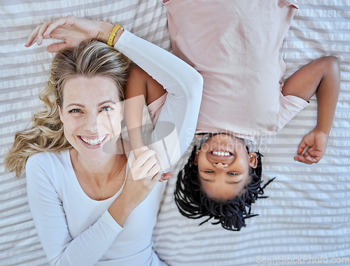 Image of Top view, family and mother with foster girl on bed, relaxing and bonding. Love, care and adoption portrait of happy mom with black kid in bedroom, smiling and enjoying quality time together in house