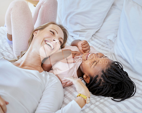 Image of Happy, adoption and mother relaxing with her child on a bed while talking, laughing and bonding. Happiness, love and mom telling her girl kid a comic joke while lying in the bedroom together at home.