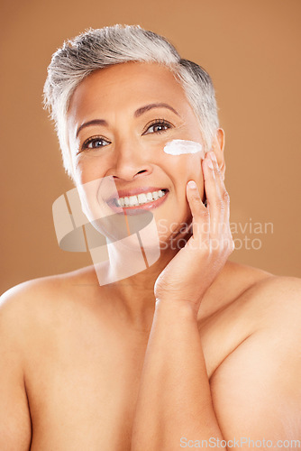 Image of Facial, cream and mature woman, skincare lotion and sunscreen, beauty and anti aging dermatology product on studio background. Portrait senior lady, face cream and cosmetics, aesthetic glow and shine