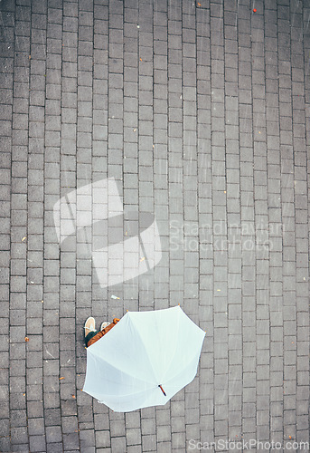 Image of Top view, rain and person with umbrella in city, street or urban road mock up. Travel, freedom and pedestrian with parasol on asphalt in winter weather traveling, standing or enjoying time outdoors