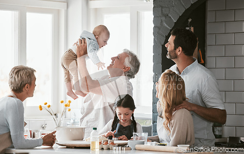 Image of .Family, kitchen and grandpa playing with baby having fun, bonding and relax together. Big family, support or care of grandfather carrying newborn with mother, father and girl child cooking in house.