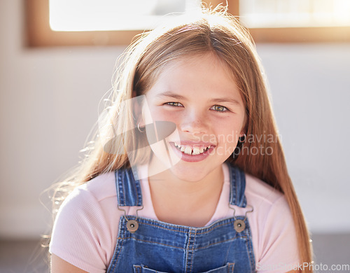 Image of Portrait, happy and girl relax at a window in a living room, cheerful an excited while sitting alone in her home. Face, child and preteen female with positive mindset relaxing with a cute smile