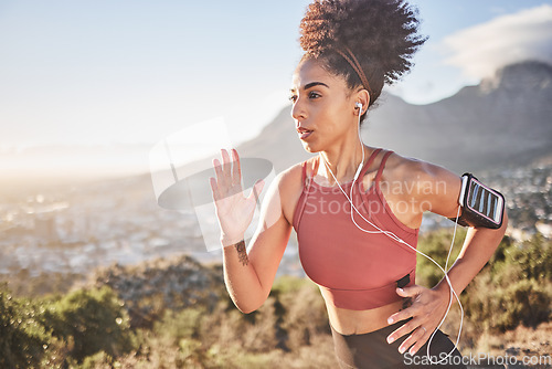 Image of Earphones, fitness and black woman running in nature outdoors streaming music, radio or podcast for motivation. Health, wellness and female runner listening to audio, song and training sound track.