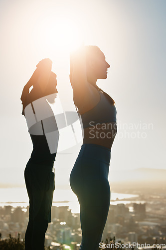 Image of Fitness, sunset and couple doing an outdoor exercise or training together on a rooftop in the city. Sports, healthy and athletes stretching before workout on roof of a building outside in urban town.