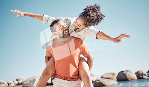 Image of Travel, happy and beach with couple and piggy back for freedom, summer and bonding. Smile, playful and airplane with man carry woman by ocean for love affection, energy and adventure on holiday