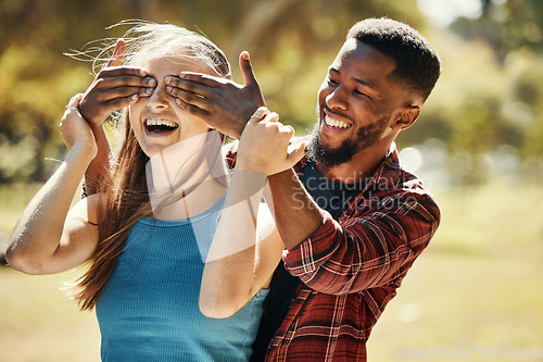 Image of Diverse, couple and man and surprise woman by covering her eyes in a nature park. Shock, wow and people having fun for anniversary surprise in a natural evironment with boyfriend and girlfriend